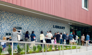 A line of people wait to enter Belmont Library on opening day