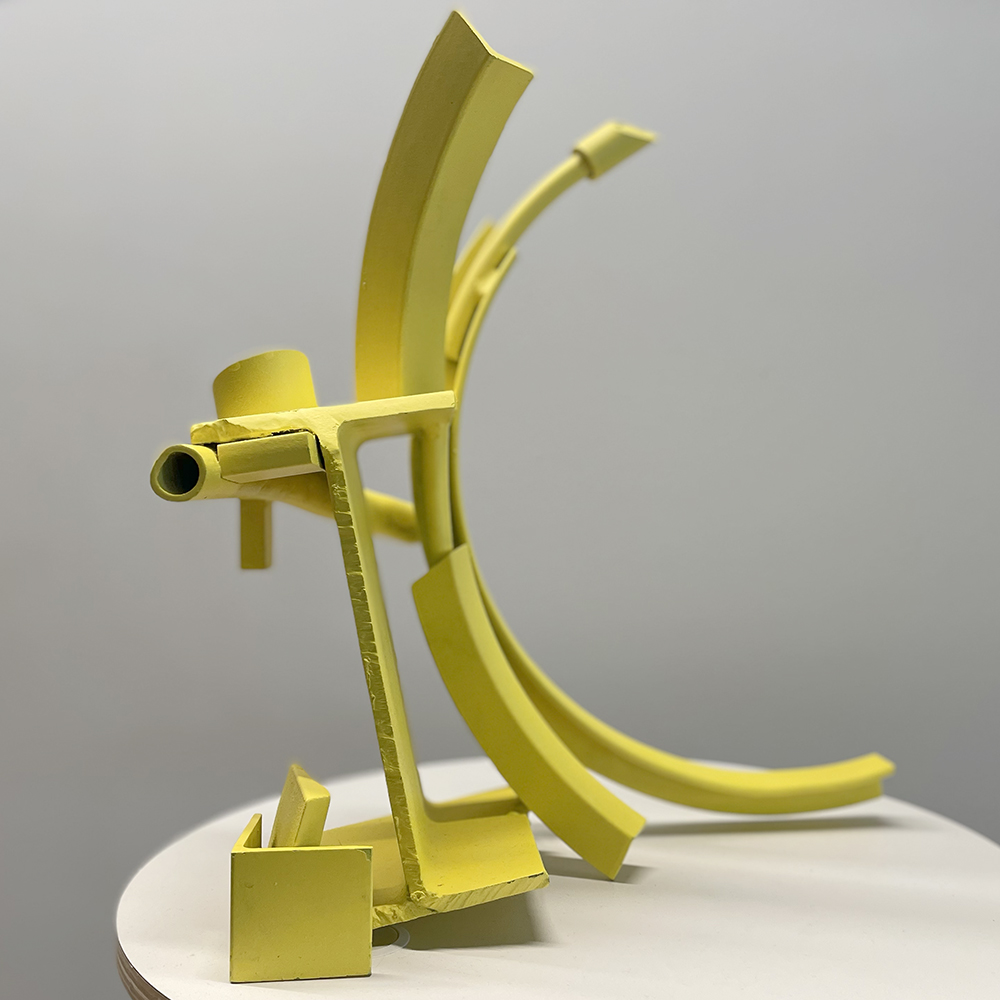 An image of a sculpture sitting on a table made from steel and painted yellow.